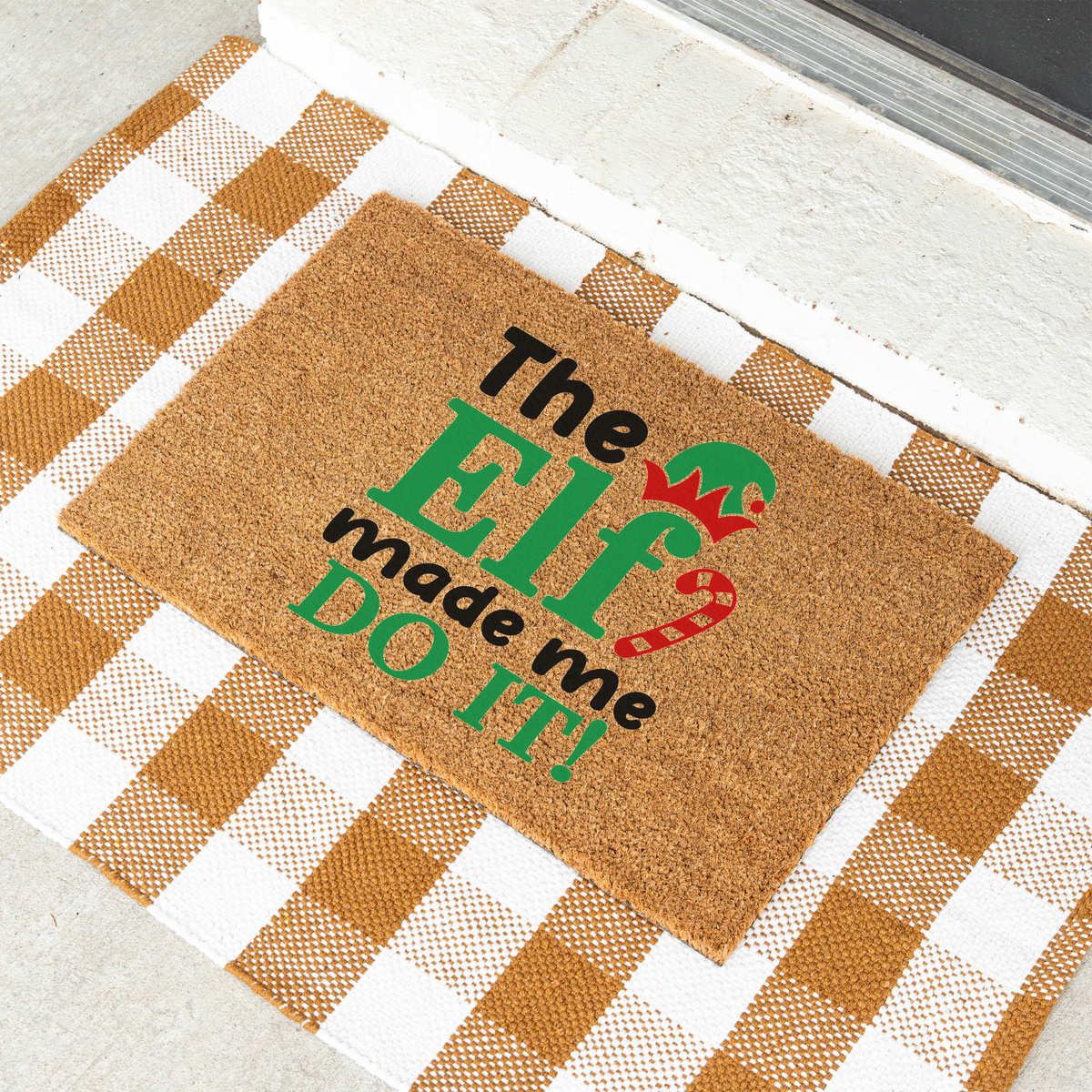 The Elf Made Me Do It coir doormat on a tan and white check rug