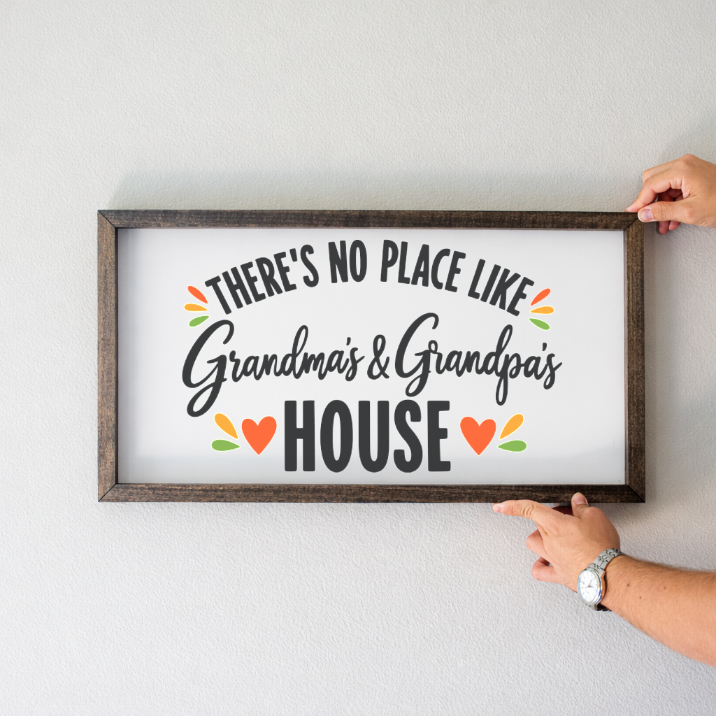 There's No Place Like Grandma's & Grandpa's House wide framed sign with a walnut frame held up on a white wall