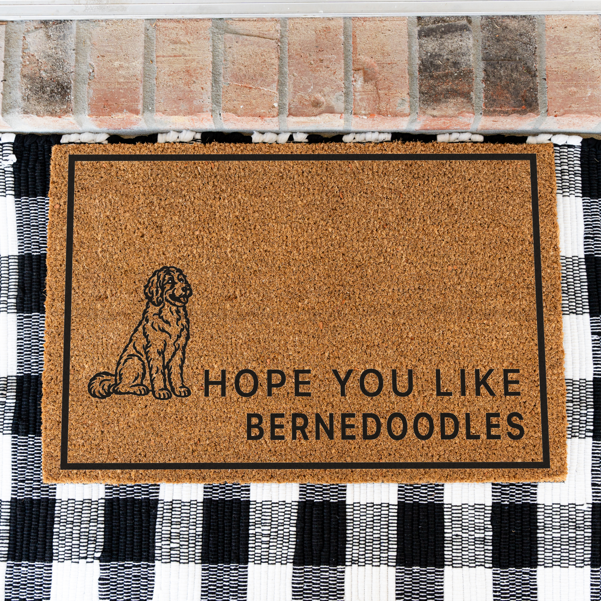 Hope You Like Bernedoodles coir doormat with a drawing of a sitting Bernedoodle on a black and white buffalo check rug, close view