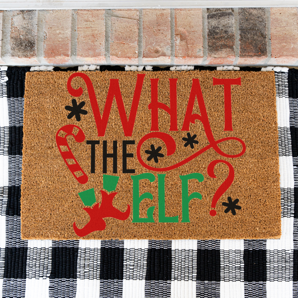 What The Elf coir doormat on a black and white buffalo check rug, close view