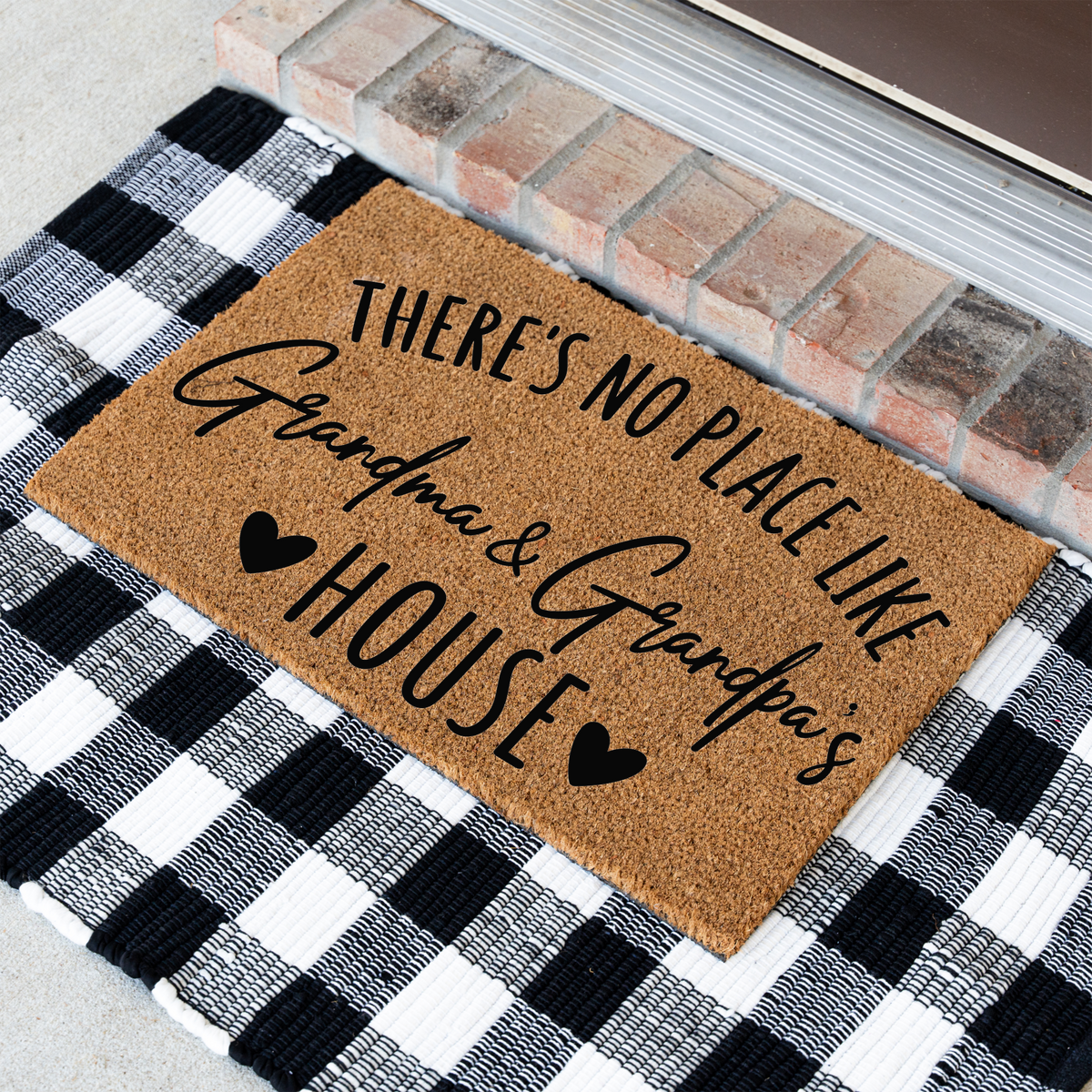 There's No Place Like Grandma & Grandpa's House coir doormat at an angle on a black and white buffalo check rug
