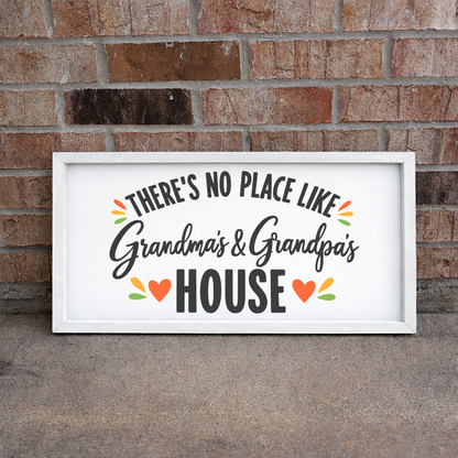 There's No Place Like Grandma's & Grandpa's House wide framed sign with a white frame leaning on a brick wall