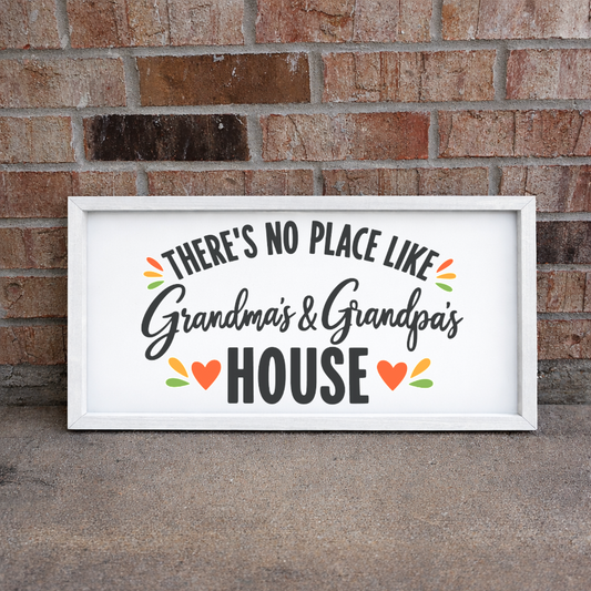 There's No Place Like Grandma's & Grandpa's House wide framed sign with a white frame leaning on a brick wall