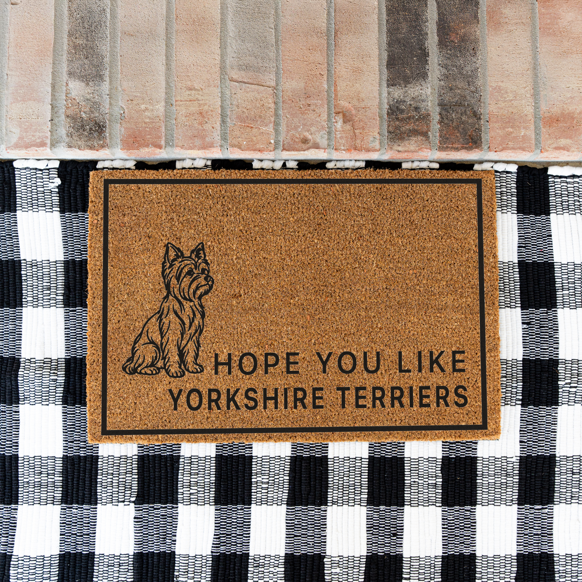Hope You Like Yorkshire Terriers coir doormat with a drawing of a sitting Yorkshire terrier on a black and white buffalo check rug at a brick step