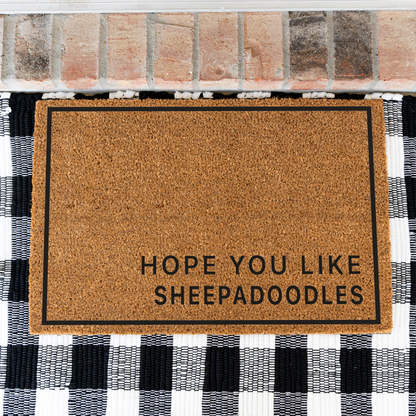 Hope You Like Sheepadoodles minimalist coir doormat with a thin black border on a black and white buffalo check rug, close view