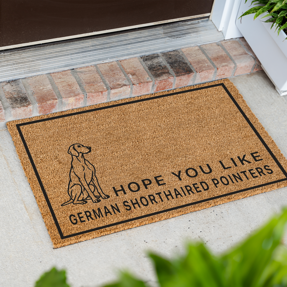 Hope You Like German Shorthaired Pointers coir doormat with a drawing of a sitting German shorthaired pointer at an angle on a front porch by a brick step