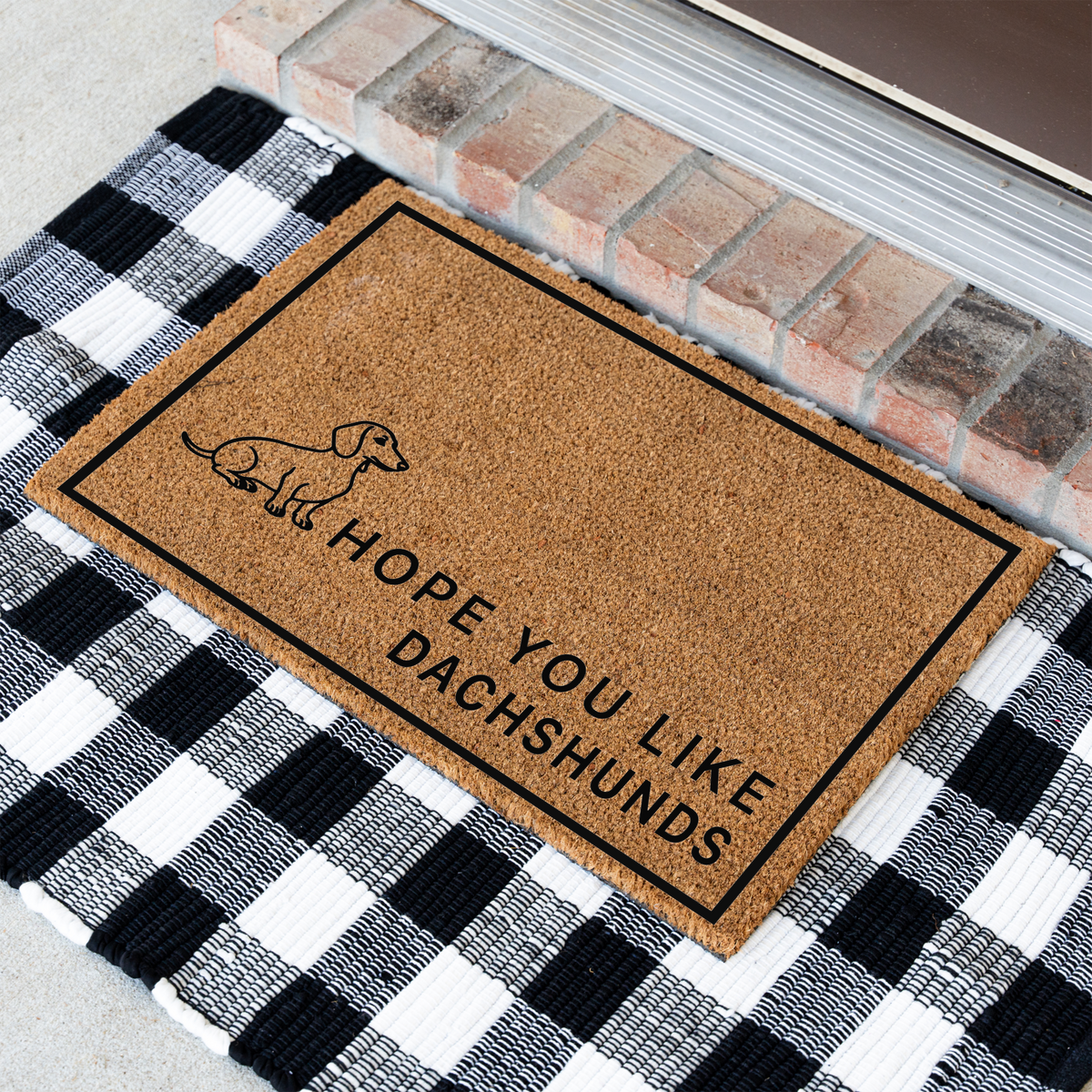 Hope You Like Dachshunds coir doormat with a drawing of a sitting dachshund at an angle on a black and white buffalo check rug