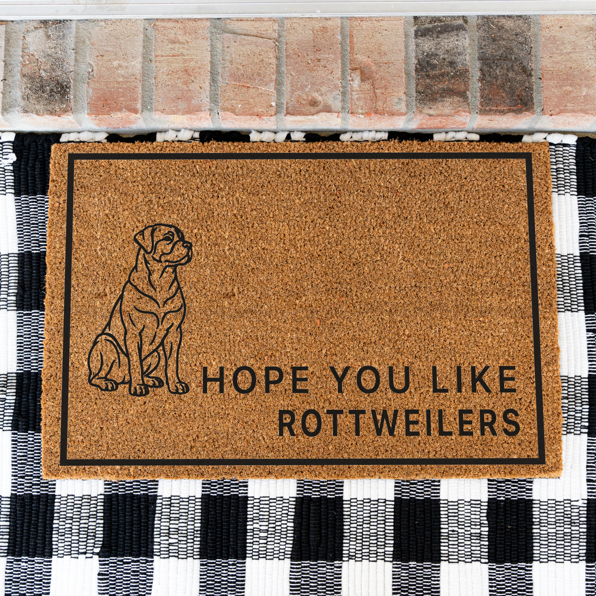 Hope You Like Rottweilers coir doormat with a drawing of a sitting Rottweiler on a black and white buffalo check rug, close view