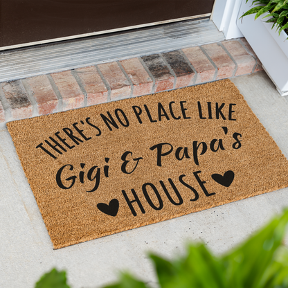 There's No Place Like Gigi & Papa's House coir doormat at an angle on a front porch by a brick step