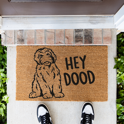 Hey Dood doodle dog coir doormat in front of a brick step, top-down view