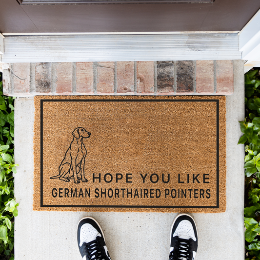 Hope You Like German Shorthaired Pointers coir doormat with a drawing of a sitting German shorthaired pointer in front of a brick step, top-down view with sneakers