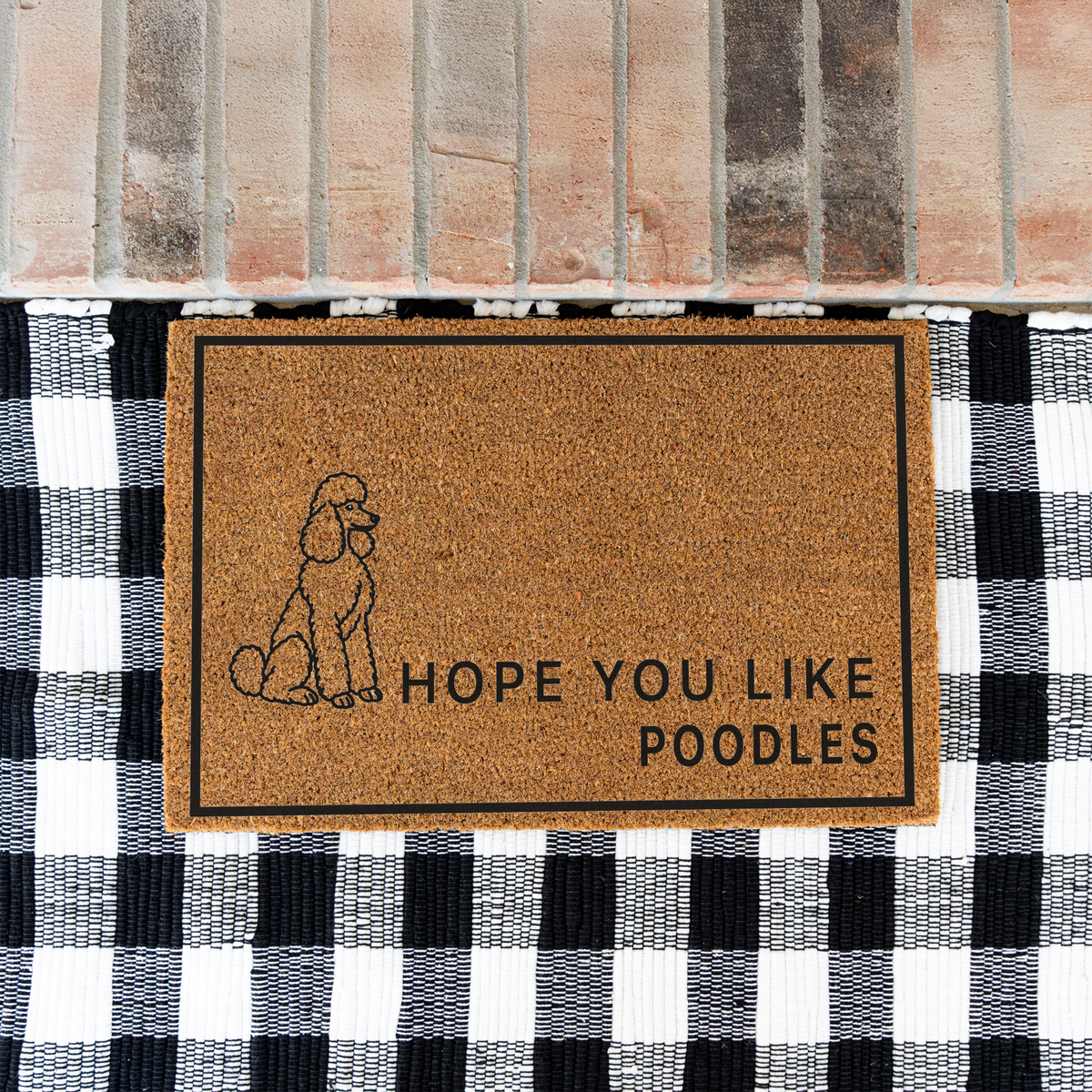Hope You Like Poodles coir doormat with a drawing of a sitting poodle on a black and white buffalo check rug at a brick step
