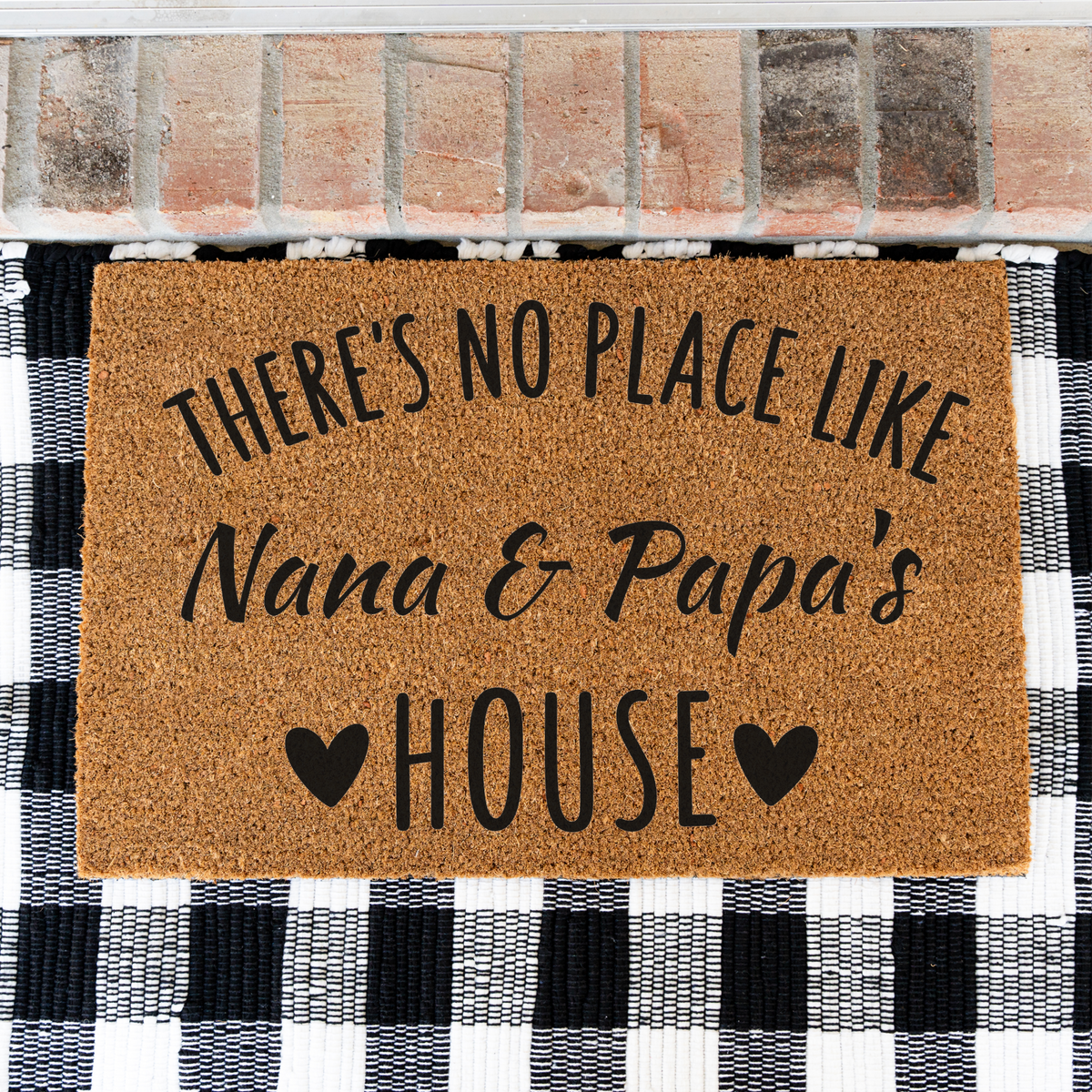 There's No Place Like Nana & Papa's House coir doormat on a black and white buffalo check rug, close view