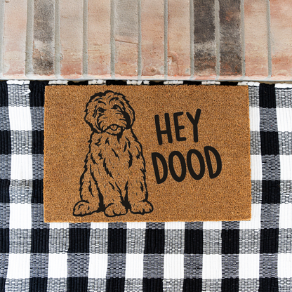 Hey Dood doodle dog coir doormat on a black and white buffalo check rug at a brick step