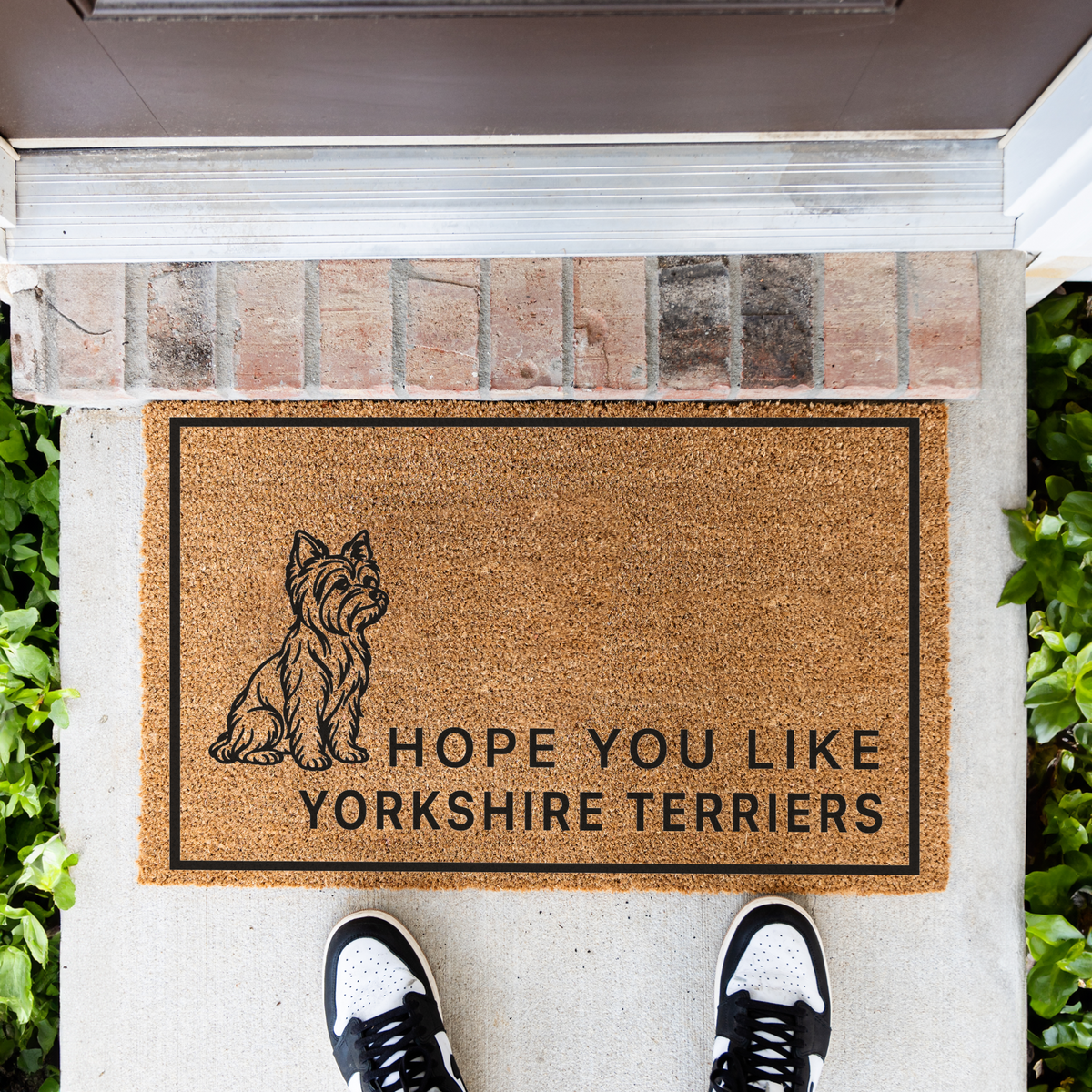 Hope You Like Yorkshire Terriers coir doormat with a drawing of a sitting Yorkshire terrier in front of a brick step, top-down view with sneakers