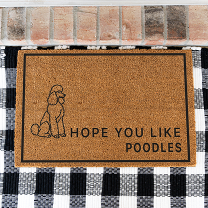 Hope You Like Poodles coir doormat with a drawing of a sitting poodle on a black and white buffalo check rug, close view