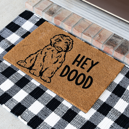 Hey Dood doodle dog coir doormat at an angle on a black and white buffalo check rug