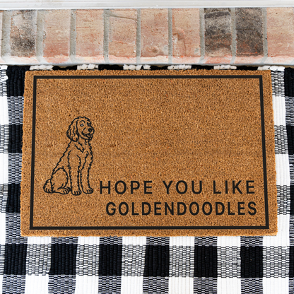 Hope You Like Goldendoodles coir doormat with a drawing of a sitting Goldendoodle on a black and white buffalo check rug, close view