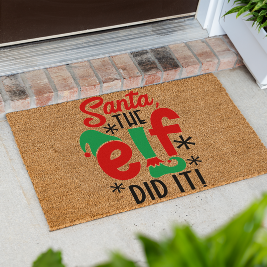 Santa The Elf Did It coir doormat at an angle in front of a brick step
