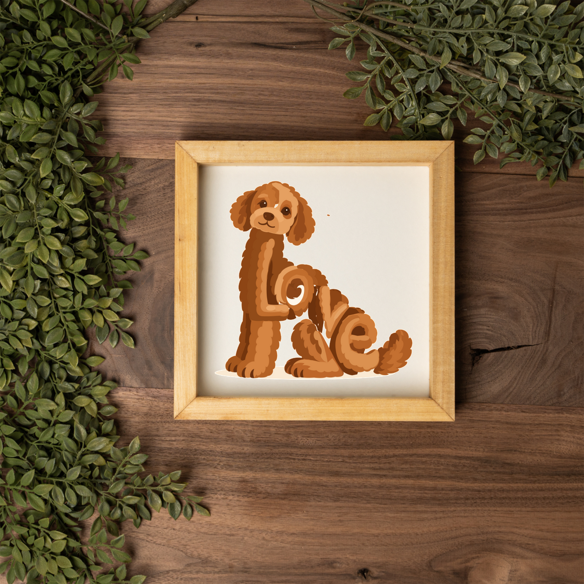 Sitting red doodle Love square framed sign with a natural wood frame on a dark wood table with greenery