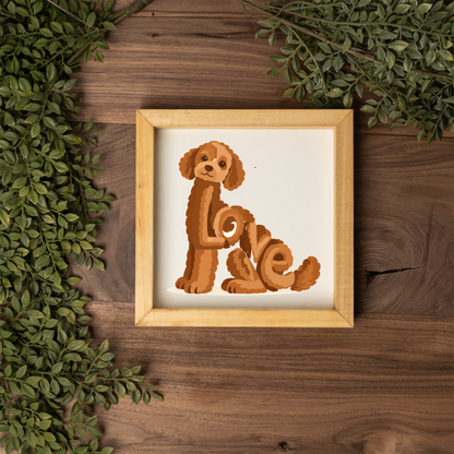 Sitting red doodle Love square framed sign with a natural wood frame on a dark wood table with greenery