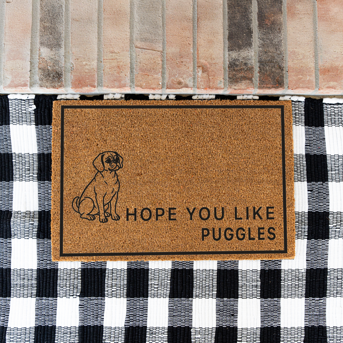 Hope You Like Puggles coir doormat with a drawing of a sitting Puggle on a black and white buffalo check rug at a brick step