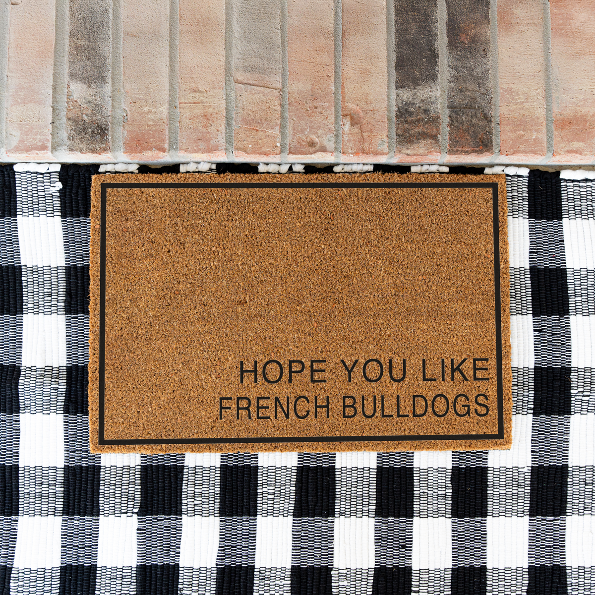 Hope You Like French Bulldogs minimalist coir doormat with a thin black border on a black and white buffalo check rug at a brick step