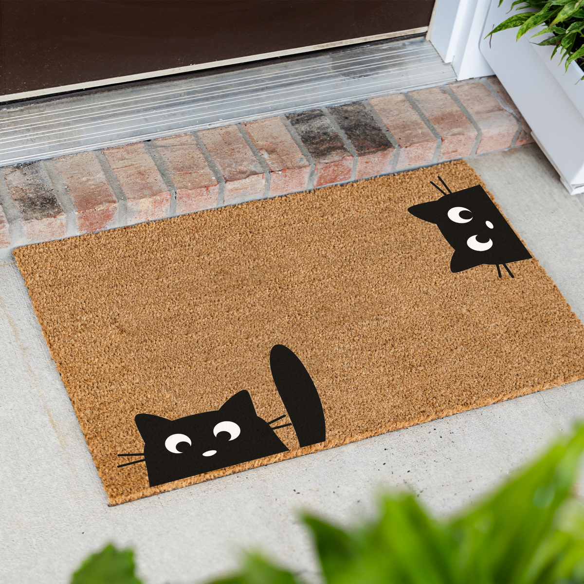 Peeking black cats coir doormat at an angle on a front porch by a brick step