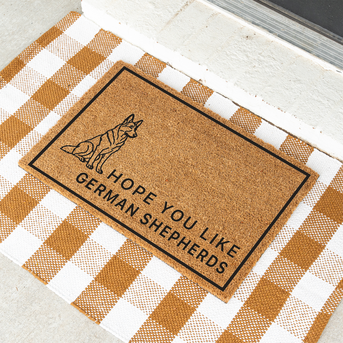 Hope You Like German Shepherds coir doormat with a drawing of a sitting German shepherd at an angle on a tan and white check rug