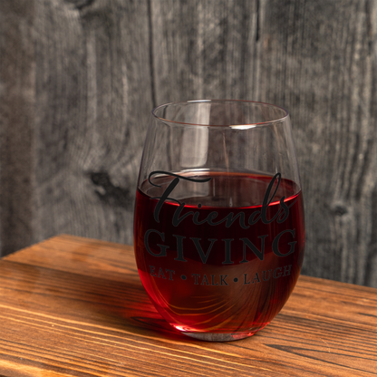 Friendsgiving stemless wine glass filled with red wine on a wood table