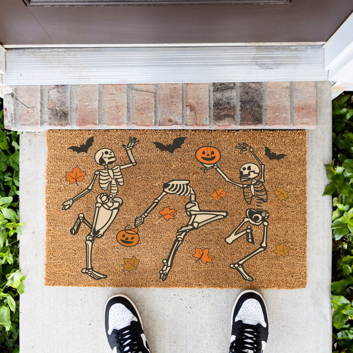 Dancing skeletons Halloween coir doormat in front of a brick step, top-down view