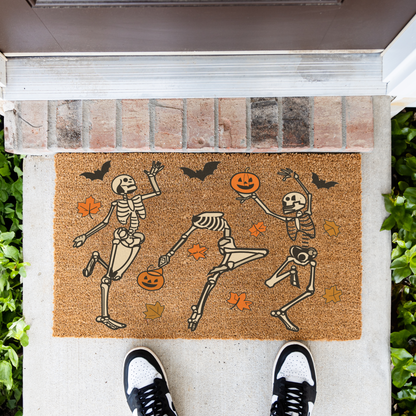 Dancing skeletons Halloween coir doormat in front of a brick step, top-down view
