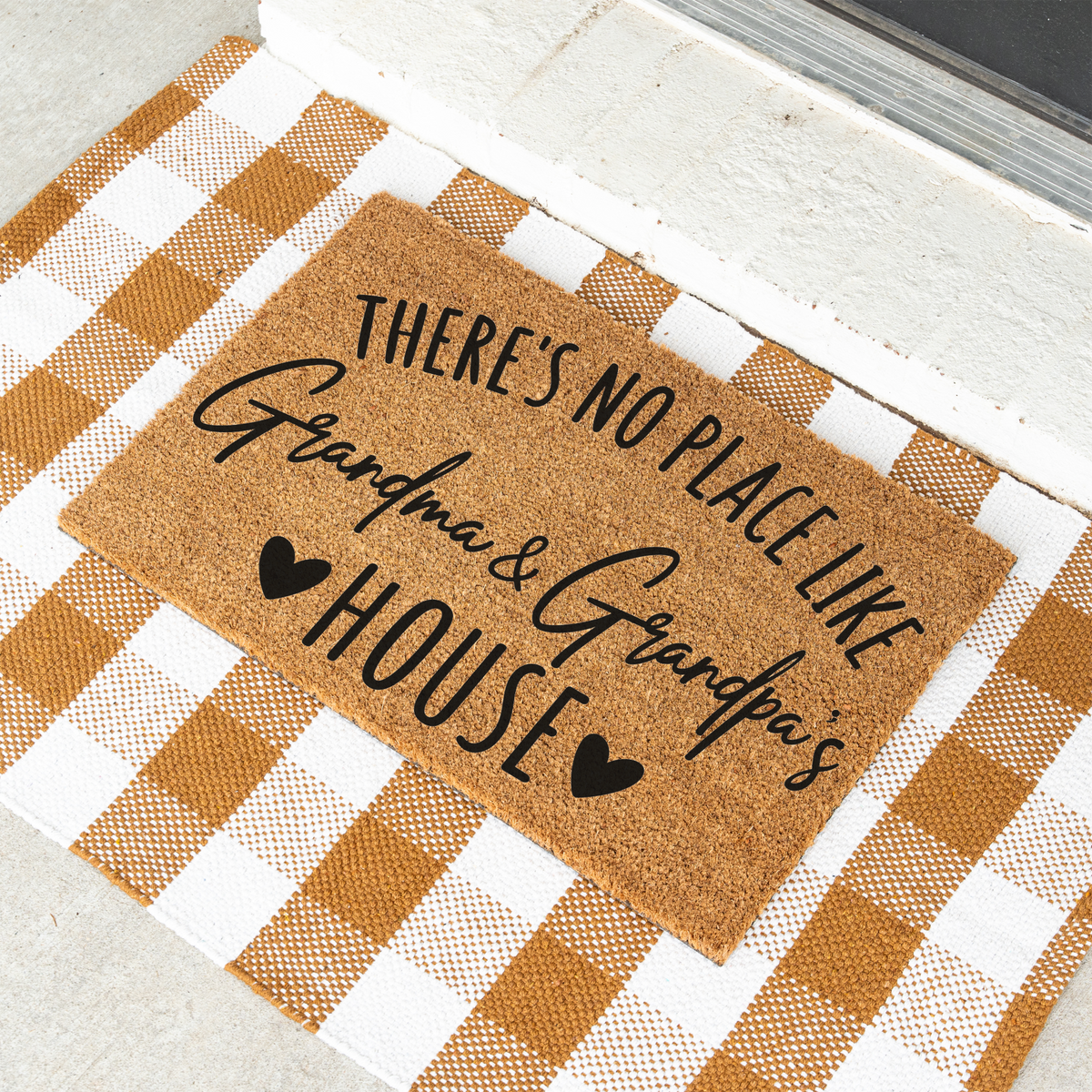 There's No Place Like Grandma & Grandpa's House coir doormat on a tan and white check rug