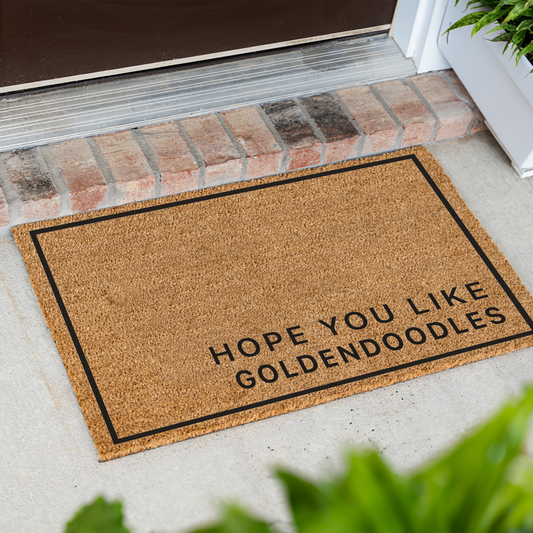 Hope You Like Goldendoodles minimalist coir doormat with a thin black border at an angle in front of a brick step