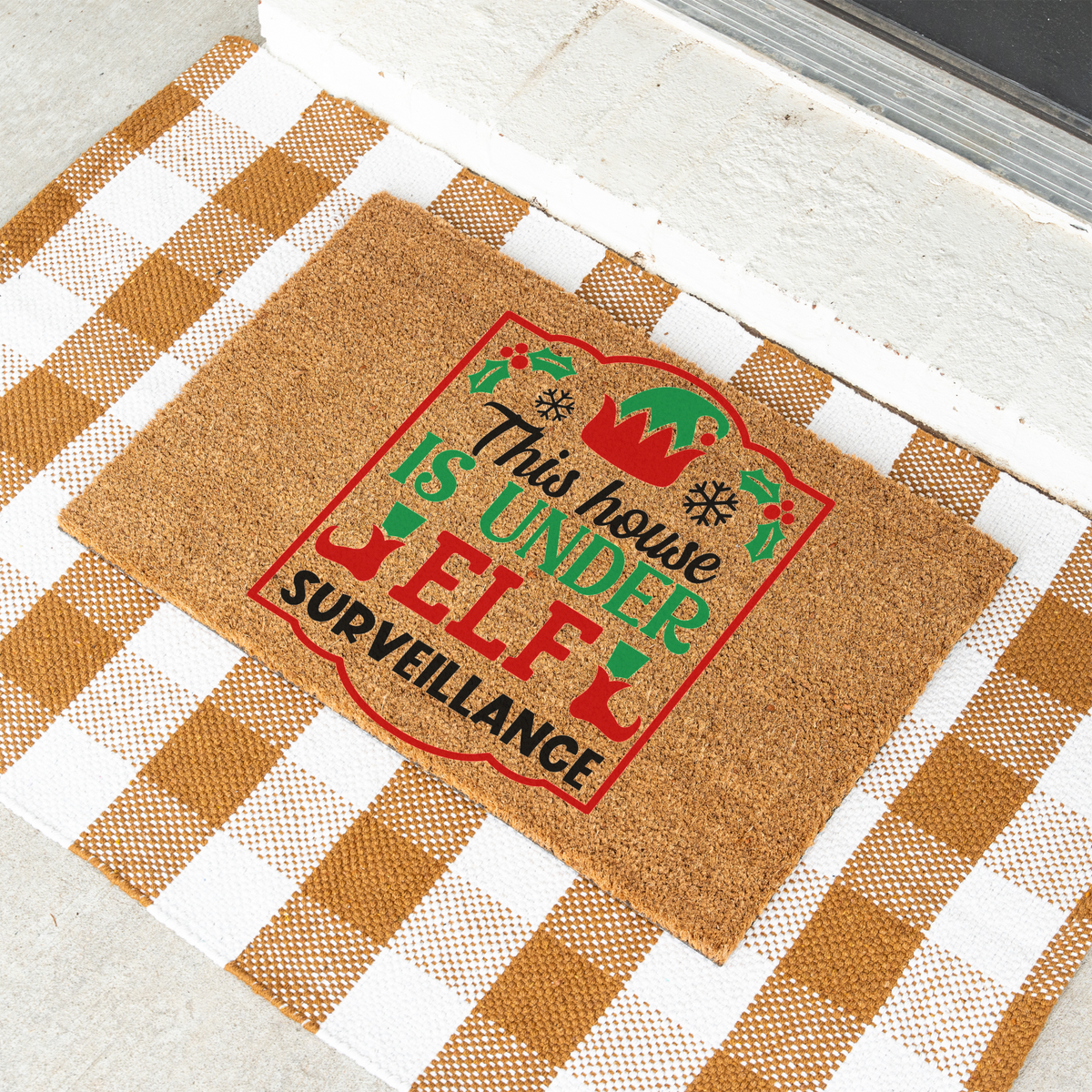 This House Is Under Elf Surveillance framed coir doormat on a tan and white check rug