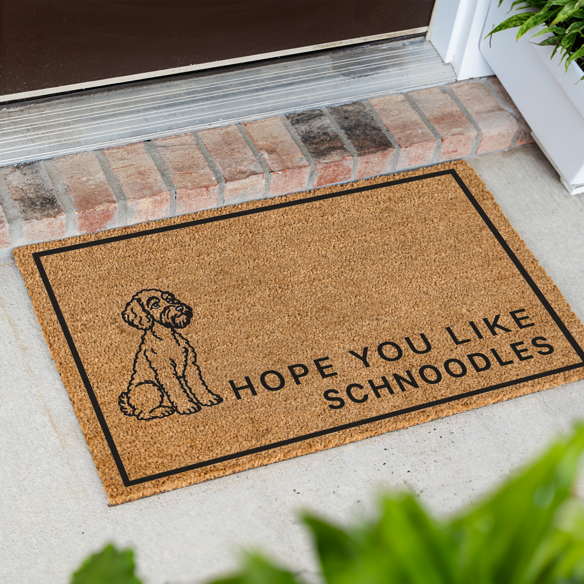 Hope You Like Schnoodles coir doormat with a drawing of a sitting Schnoodle at an angle on a front porch by a brick step