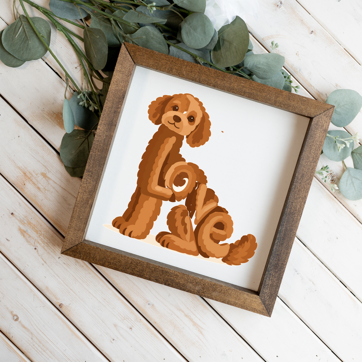 Sitting red doodle Love square framed sign with a walnut frame on white wood planks with eucalyptus