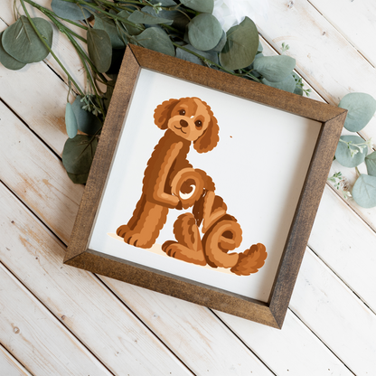 Sitting red doodle Love square framed sign with a walnut frame on white wood planks with eucalyptus