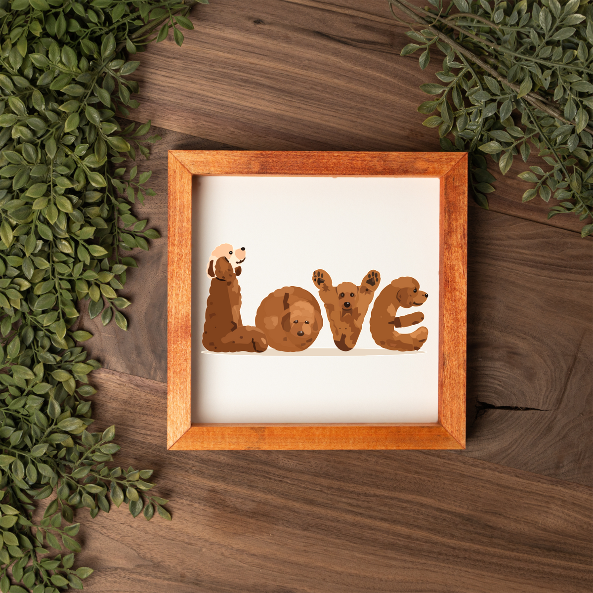 Four red doodles spelling LOVE square framed sign with a stained wood frame on a dark wood table with greenery