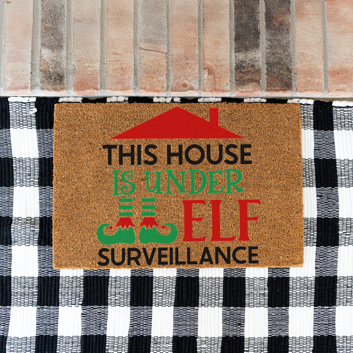 This House Is Under Elf Surveillance coir doormat on a black and white buffalo check rug at a brick step