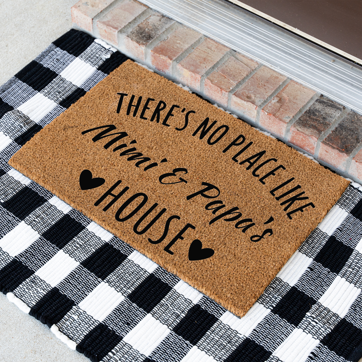There's No Place Like Mimi & Papa's House coir doormat at an angle on a black and white buffalo check rug