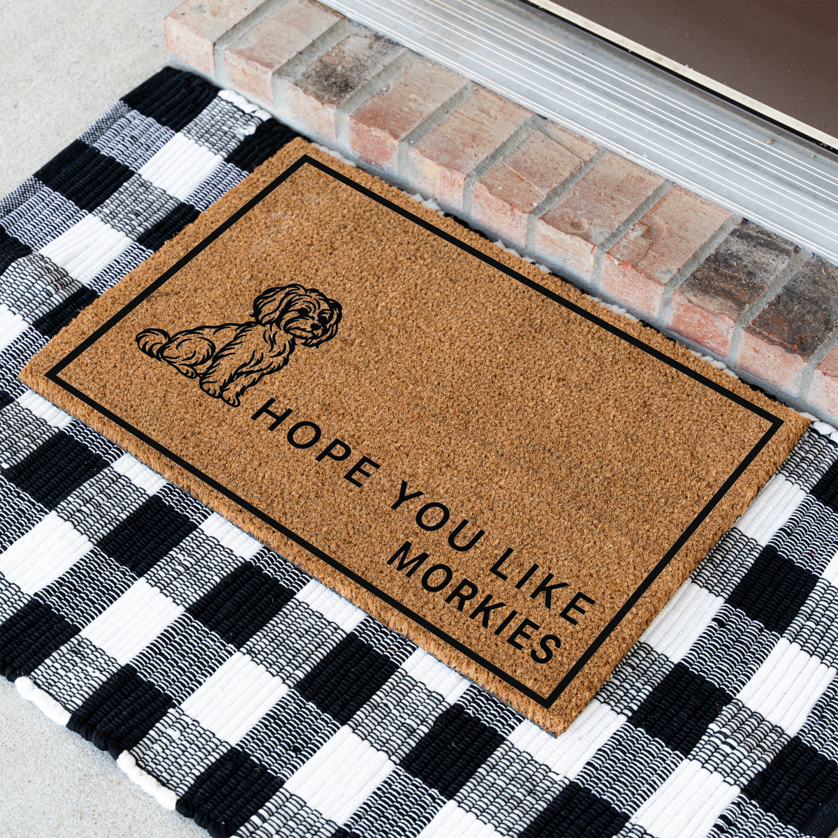 Hope You Like Morkies coir doormat with a drawing of a sitting Morkie at an angle on a black and white buffalo check rug