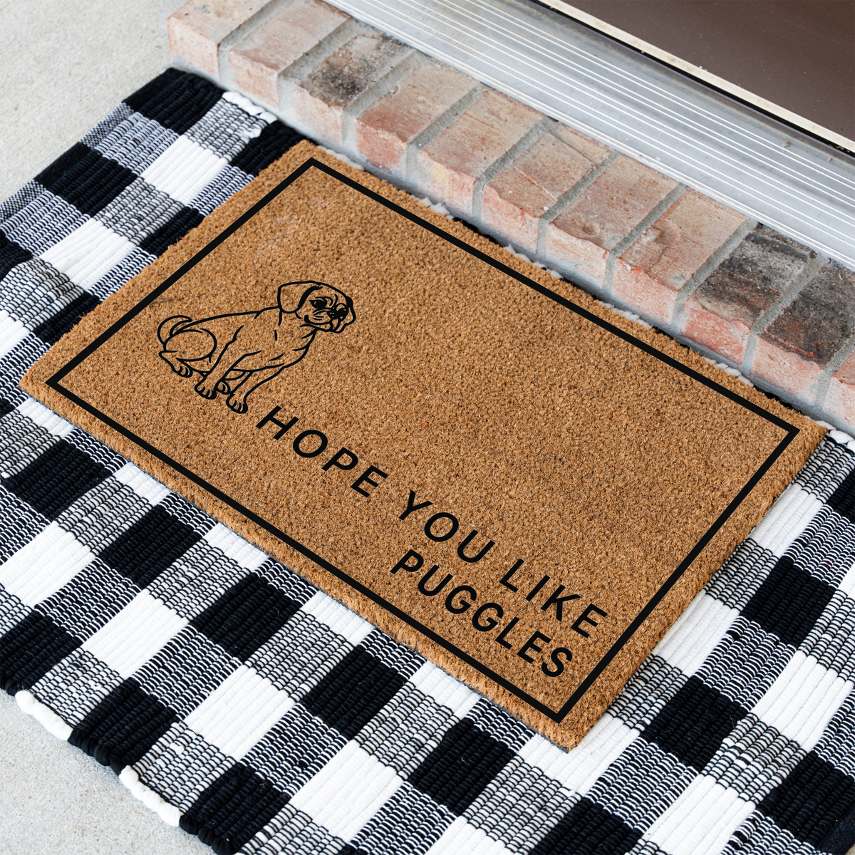 Hope You Like Puggles coir doormat with a drawing of a sitting Puggle at an angle on a black and white buffalo check rug