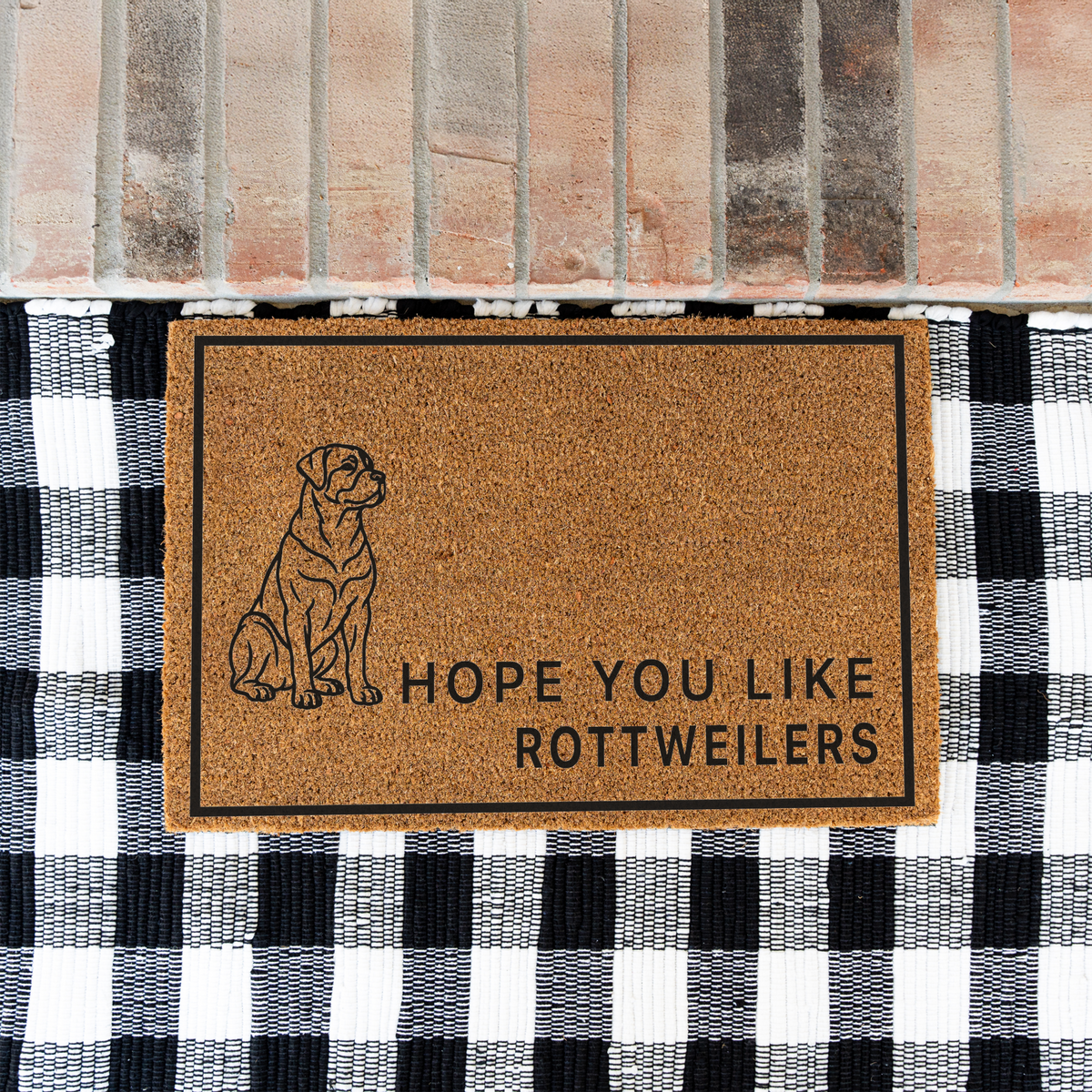 Hope You Like Rottweilers coir doormat with a drawing of a sitting Rottweiler on a black and white buffalo check rug at a brick step