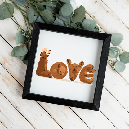 Four red doodles spelling LOVE square framed sign with a black frame on white wood planks with eucalyptus