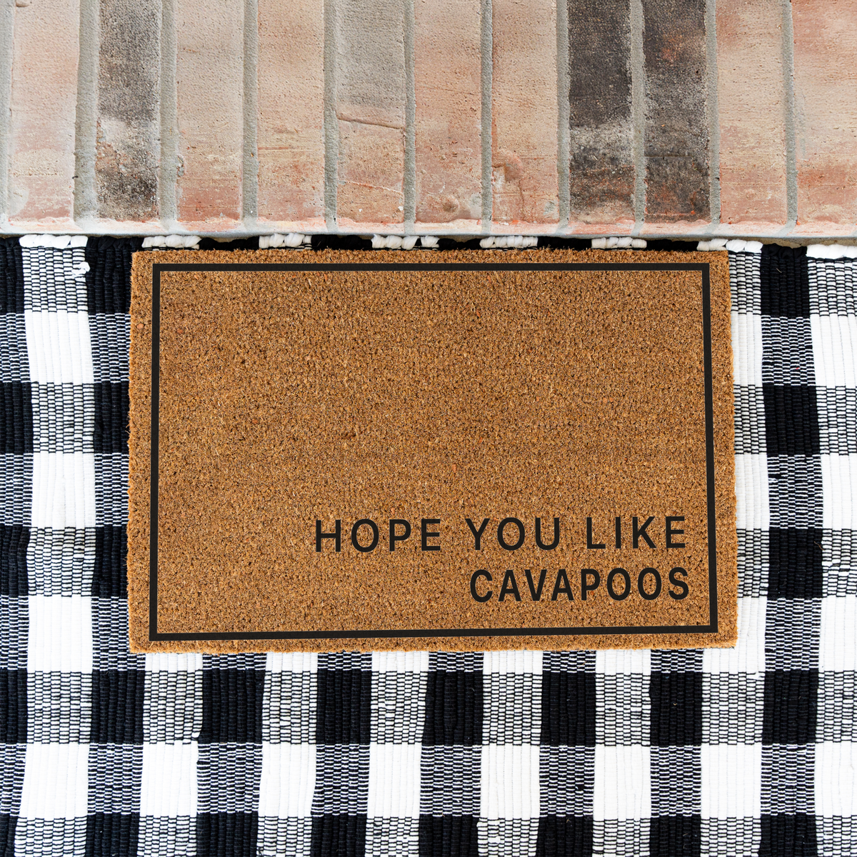 Hope You Like Cavapoos minimalist coir doormat with a thin black border on a black and white buffalo check rug at a brick step