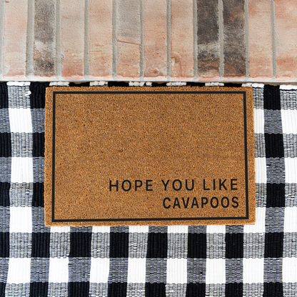 Hope You Like Cavapoos minimalist coir doormat with a thin black border on a black and white buffalo check rug at a brick step