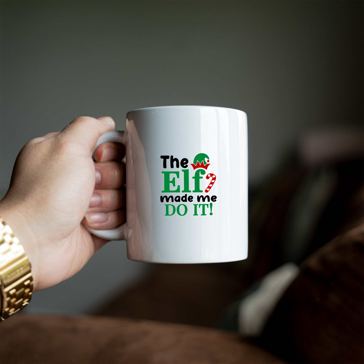 The Elf Made Me Do It white ceramic Christmas coffee mug held in a hand