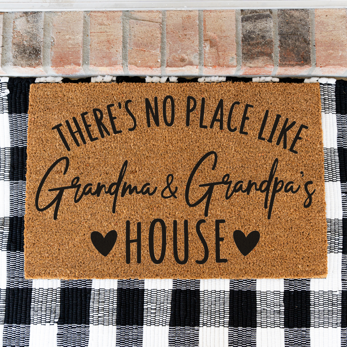 There's No Place Like Grandma & Grandpa's House coir doormat on a black and white buffalo check rug, close view