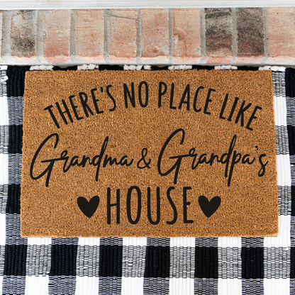 There's No Place Like Grandma & Grandpa's House coir doormat on a black and white buffalo check rug, close view